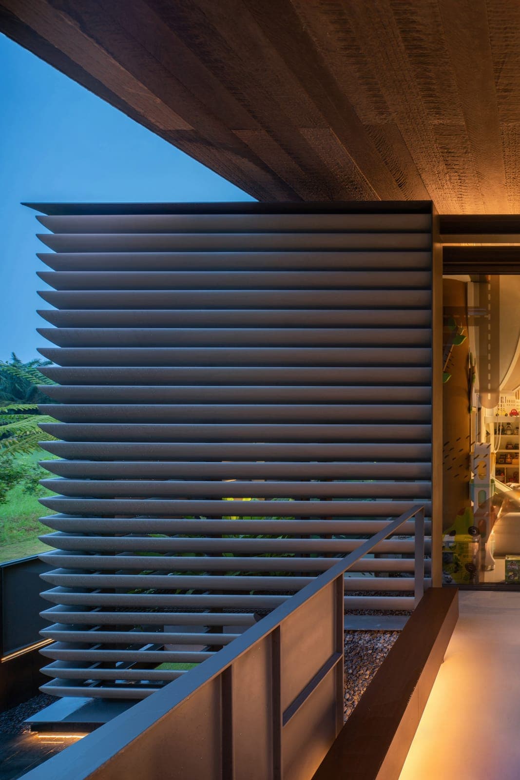 Aluminium louvres standing off the glass at dusk.