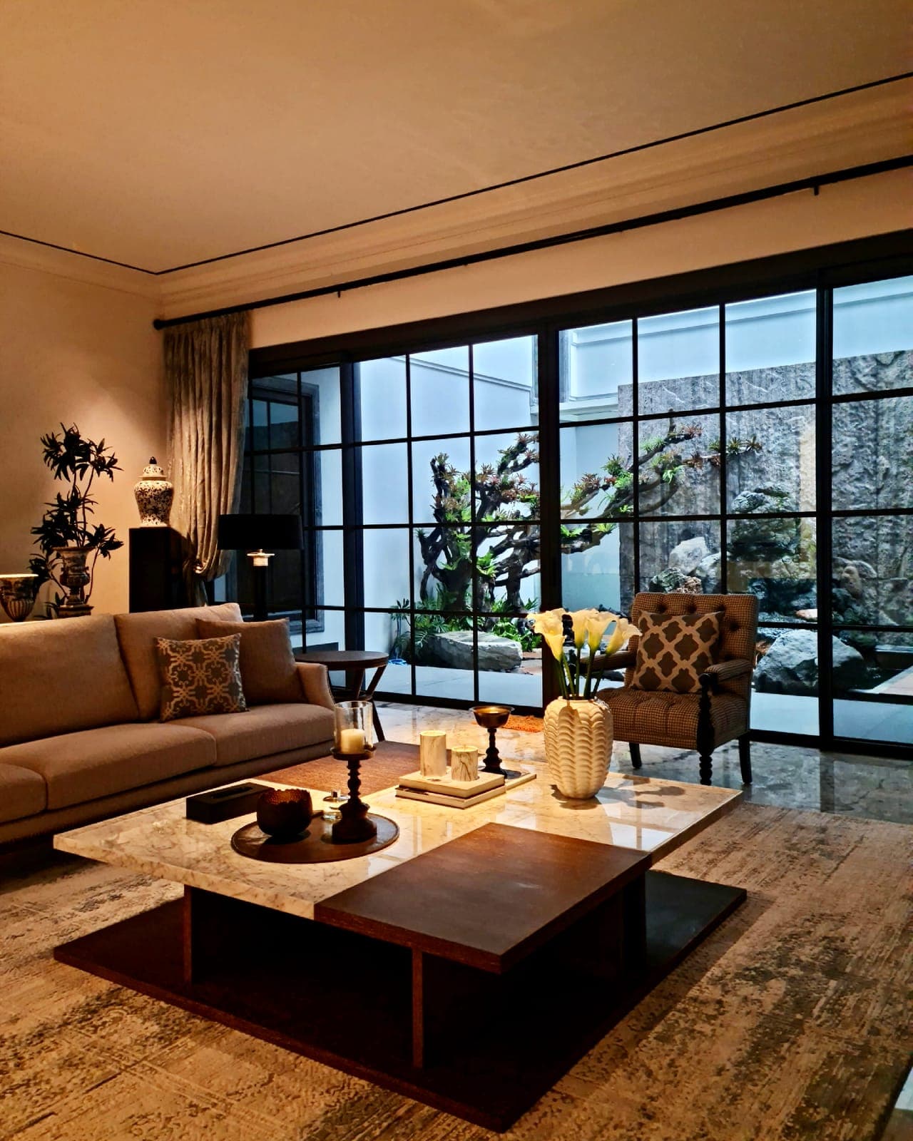 The living room, its gridded wall open to a courtyard of rock and trained pine.