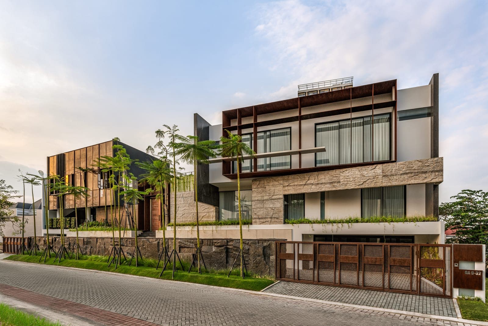 The street front at dusk: split stone and banded marble under a bronze-framed upper storey.