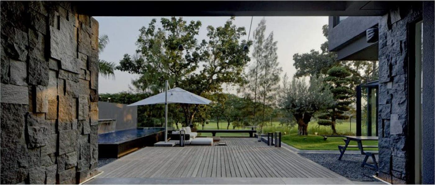 From the covered terrace the same frameless threshold runs out to timber decking and the golf course beyond.