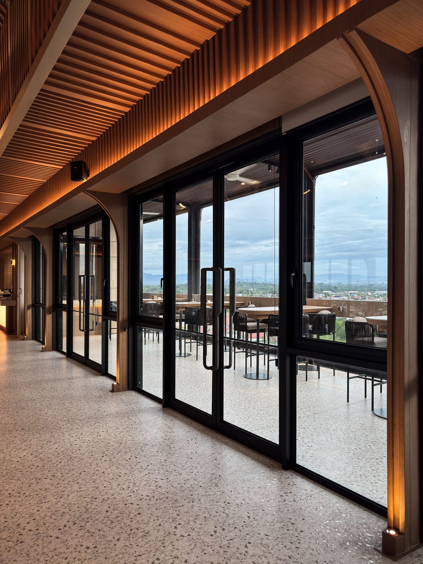 The sky lounge arcade — arched openings carrying full-height glazed doors onto the terrace.