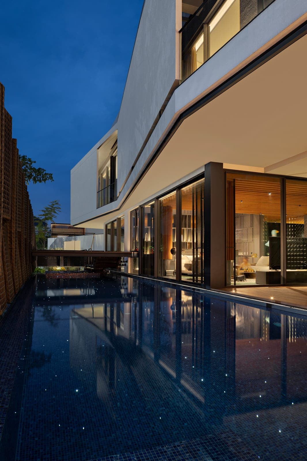 The same water at dusk, the whole flank of the house lit.