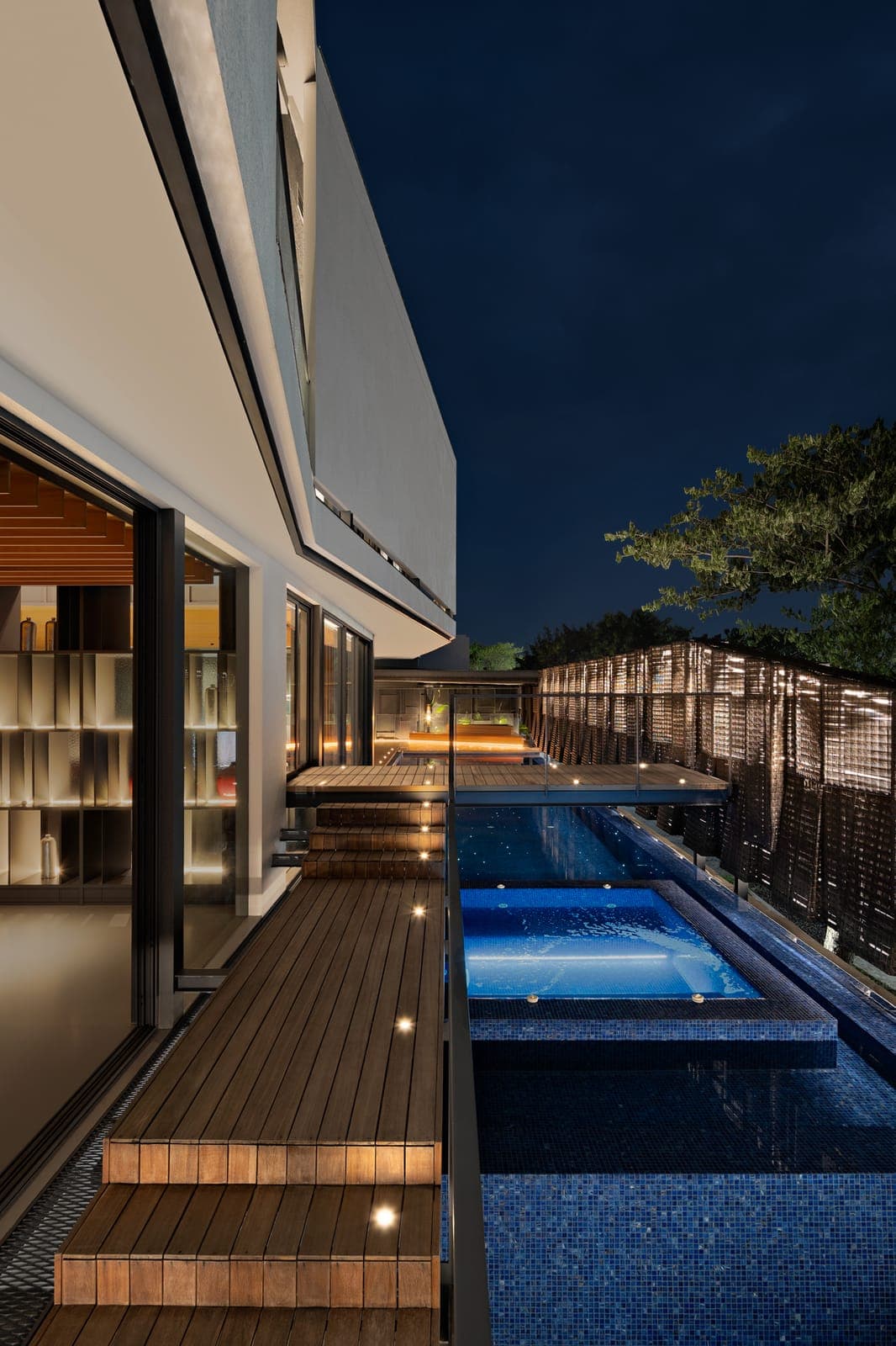 Timber steps to the water, the brick screen uplit behind.